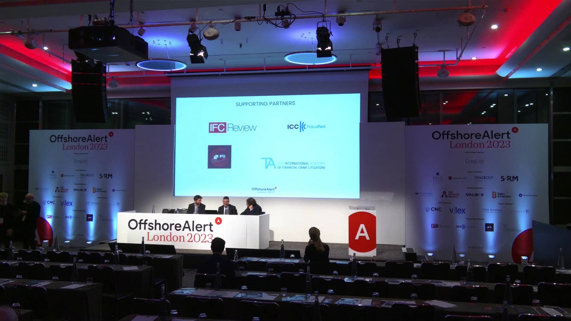 people on conference stage with printed signage around them
